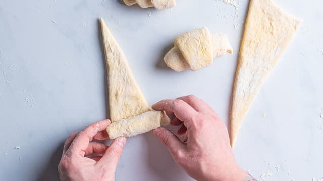 Rull sammen hver trekant til en croissant ved å rulle fra den brede enden mot spissen.
