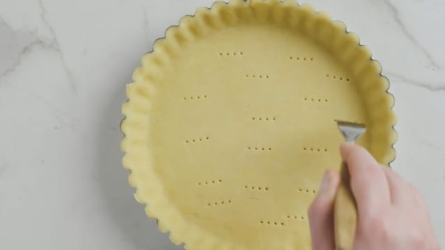 Kjevle så ut deigen og kle en form, ca 24 cm, helt opp til kantene, bruk ildfast paiform eller kakeform. Fjern eventuelt overflødig deig. Prikk bunnen med en gaffel. Stek bunnen midt i ovnen ved 200 grader i 15 minutter.