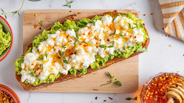 Topp brødskivene med most avokado, cottage cheese og hot honey.
