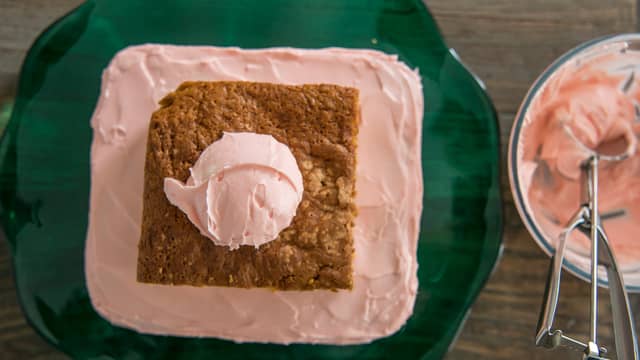 Smør frosting på den største kakedelen, legg på den andre og dekk hele kaken med frosting.