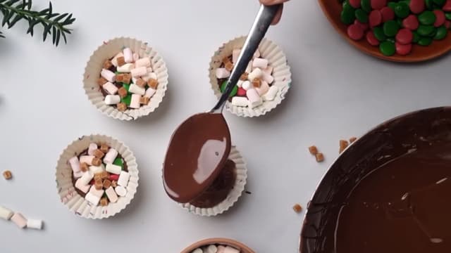 Hell resten av den smeltede sjokoladen over i muffinsformene. Stikk en teskje ned i sjokoladen og la sjokoladen stivne.