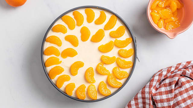 Ta ostekaken ut av kjøleskapet, og legg mandarinbåtene på toppen av kaken.