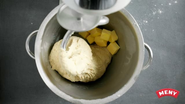 Elt med eltekrok i 15 minutter på lav hastighet til deigen slipper bollen. Ha eventuelt i mer mel til deigen slipper bollen. Tilsett smør i terninger, og elt videre i ca. 10 min til.