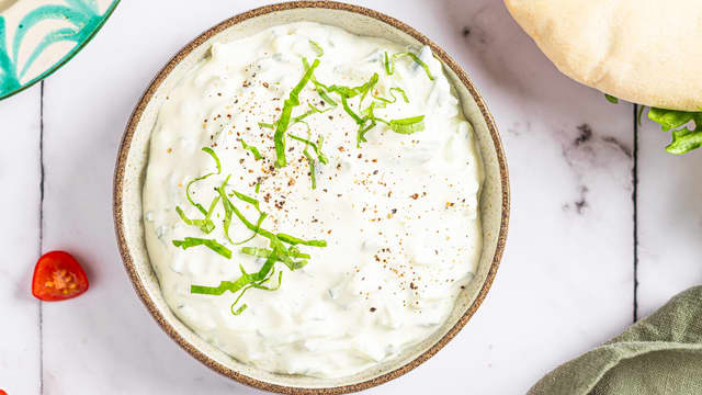 Finhakk hvitløksfeddene og bland med agurk og yoghurt. 400g yoghurt tilsvarer ca 4 dl. Smak til med skall og saft fra sitronen, salt og pepper.