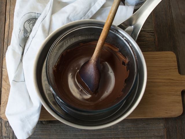 **Kokosboller:** Når kokosbollene er stive smelter du kokesjokolade og delfiafett over vannbad. Rør til du får en glatt masse. Avkjøl til det så vidt begynner å stivne.