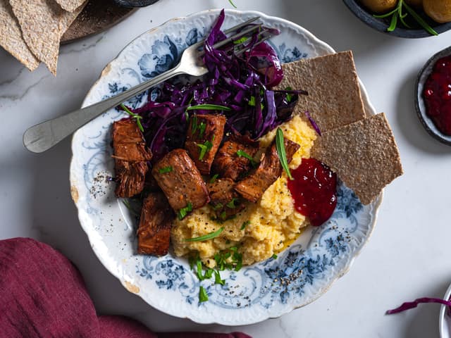 Server med klassisk tilbehør, som rødkål, kålrabistappe, tyttebærsyltetøy og flatbrød.