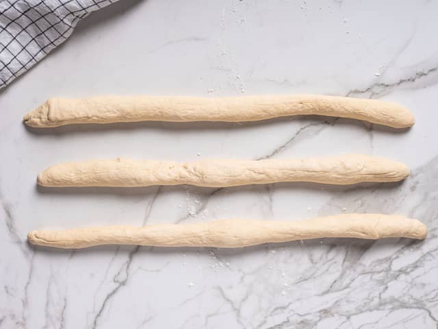 Elt deigen godt og del den i tre like store deler. Trill dem til pølser, ca 20 cm lange.