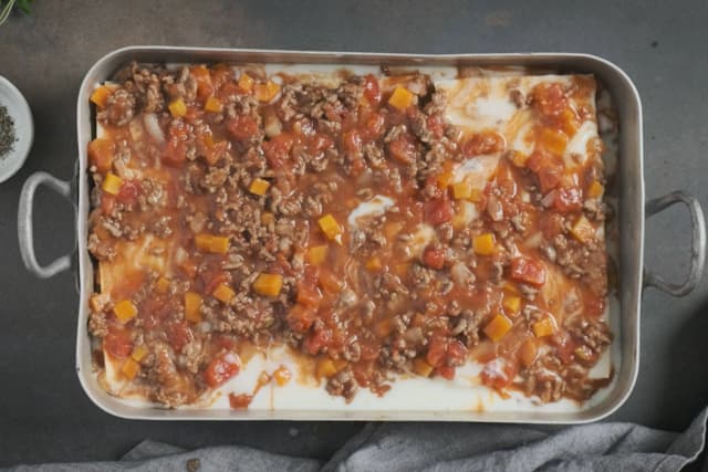 **Lasagne:** Legg kjøttsaus, lasagneplater og ostesaus lagvis i en ildfast form. Topp med revet ost.