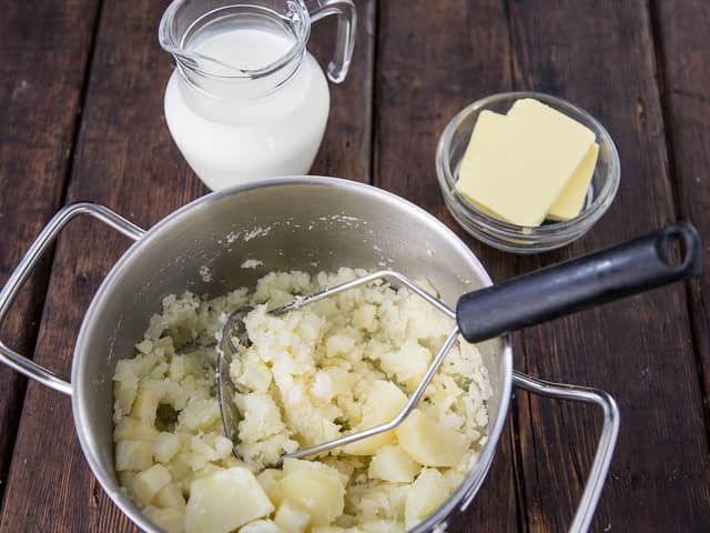 Tilsett smør og melk og bruk en potetmoser for å få mos. Smak til med salt og pepper.