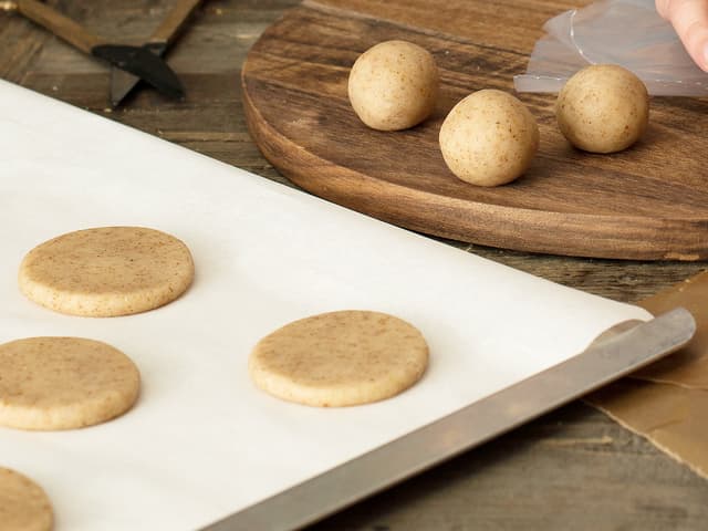 Form deigen til kuler og legg dem på et bakebrett med bakepapir. Press kulene flate.