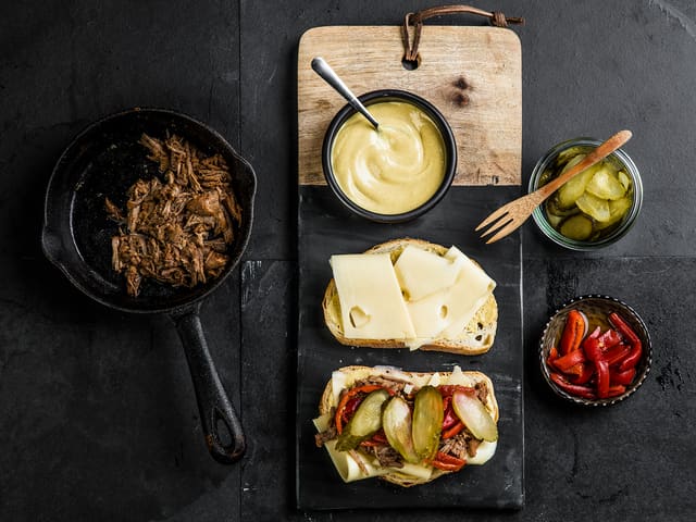 Smør loffskivene med sennep og legg på ost. Legg pulled pork krydret
med spisskummen, sylteagurk og paprika på den ene osteskiven.