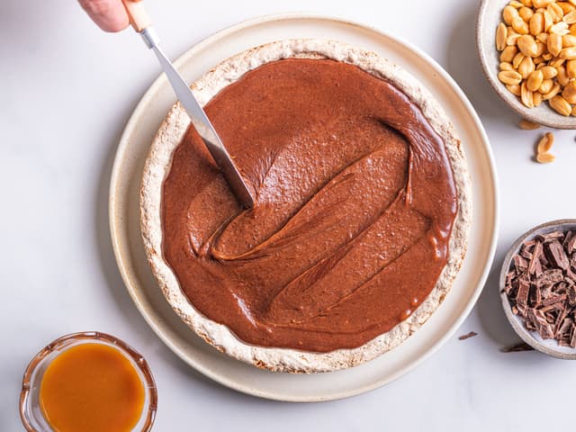 **Snickersglasur:** Bre sjokoladekremen over den avkjølte kakebunnen.