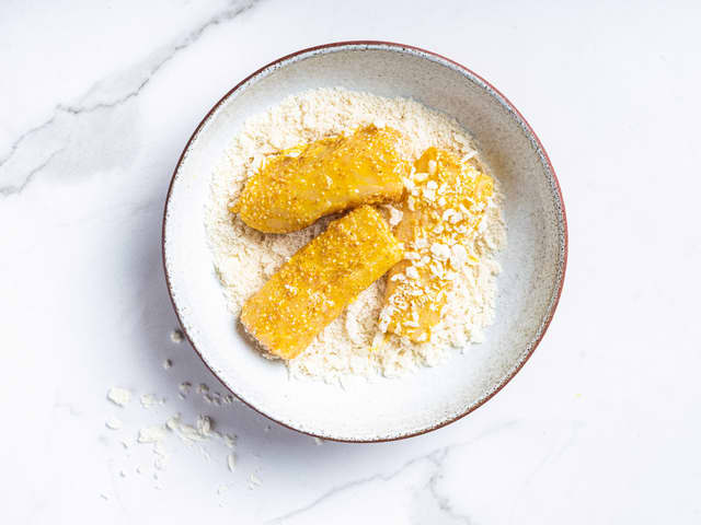 Dypp fiskestykkene i mel, deretter egg og så griljermel til slutt. Legg så de ferdigpanerte fiskestykkene på en tallerken med kjøkkenpapir til de skal stekes.