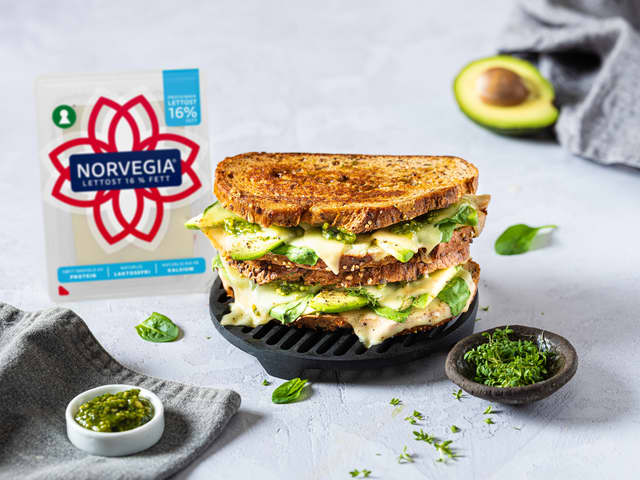 Skrell og del avokado i tynne skiver, fordel på de to skivene. Legg lagvis over spiser, spinat og til slutt ost. Dryss over pepper.