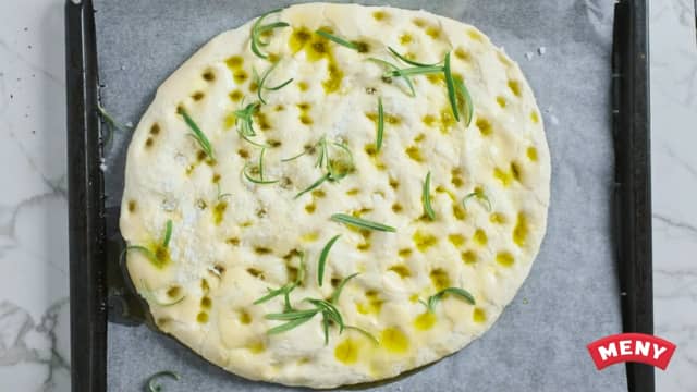 Fordel resten av oljen over brødet og strø over flaksalt og urter. Del tomatene i to og sett de godt ned i brødet.