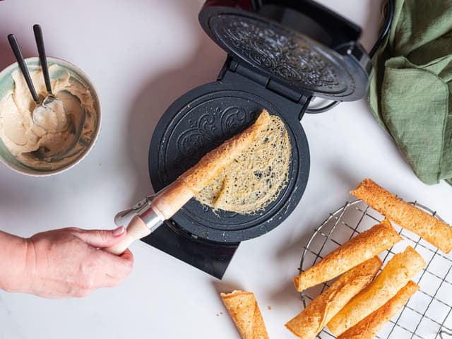 Kakene stekes gylne og formes til kremmerhus ved hjelp av en krumkakepinne.