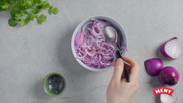 **Syltet rødløk:** Bland honning og bringebæreddik godt sammen med en gaffel, og legg tynne skiver av rødløk oppi. La stå mens du lager resten av maten.