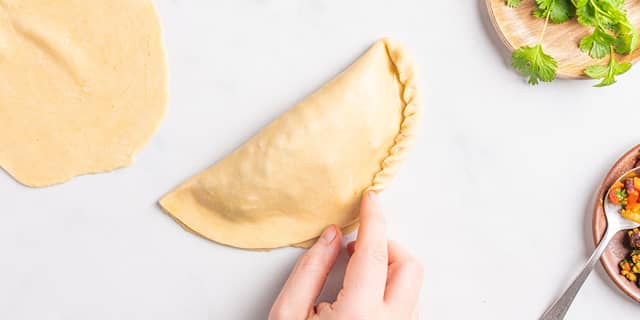 Brett sammen kanten rundt slik at du får en pen kant. Pensle empanadasene med egg og strø på sesamfrø.