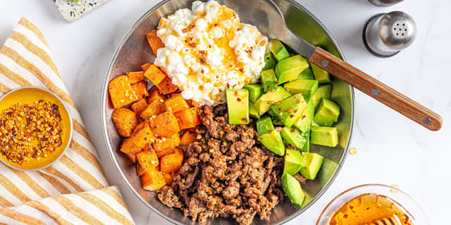 Anrett stekt kjøttdeig, bakt søtpotet, avokado og cottage cheese på to tallerkener eller i to boller. Topp med hot honey.