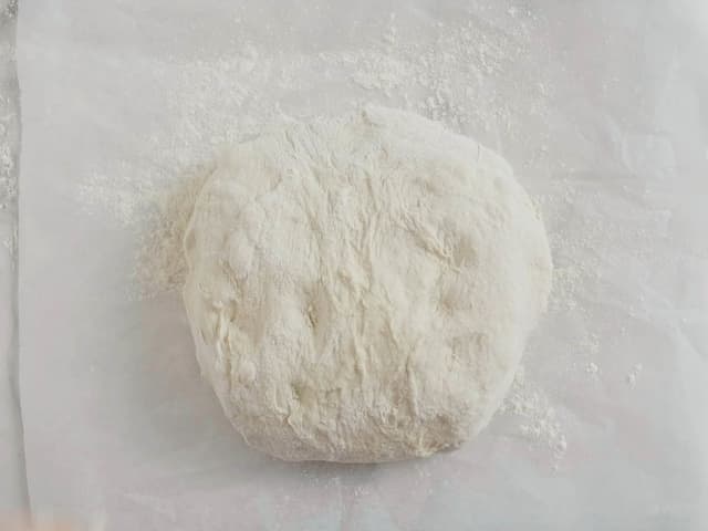 Legg deigen over på et bakepapir med bretteskjøtene ned. Dekk med et kjøkkenhåndkle og la deigen etterheve i 2 timer.