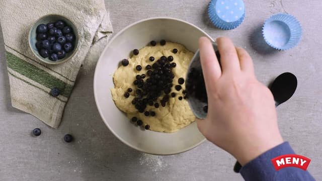 Vend inn blåbærene med skje eller slikkepott. Ha deretter røren i muffinsformer