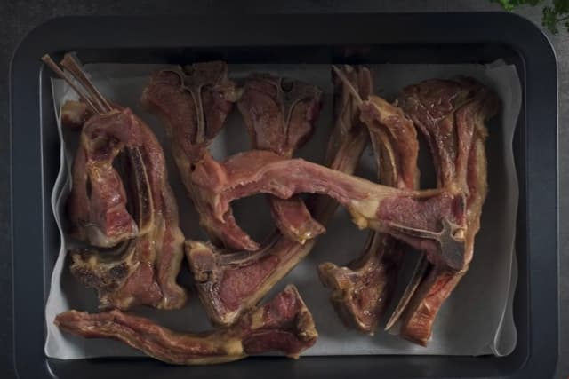 Ta pinnekjøttet opp fra kjelen, og ta vare på kraften. Pensle kjøttstykkene med flytende honning på begge sider og legg dem pent i en langpanne dekket med bakepapir. **Sett pinnekjøttet høyt i ovnen på grillfunksjon i 2-3 minutter** på hver side før servering.