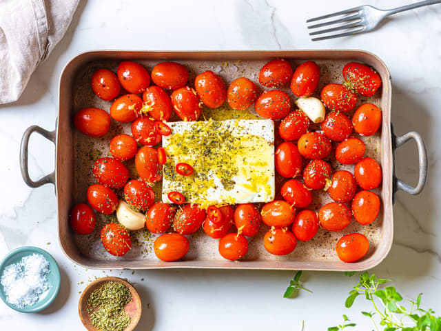 Plasser fetaosten midt i formen. Ha over resten av oljen, saltet og pepperet. Dryss over oregano og sitronskall.