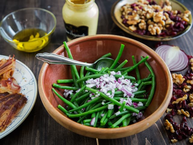 **Bønnesalat:** Fosskok bønnene i godt saltet vann i 1 minutt. Hell av vannet og ha bønnene i en bolle sammen med finhakket rødløk, bacon fra kalkunbrystet, valnøtter og tørkede tranebær. Lag en vinaigrette av olivenolje, dijon og sitronsaft og vend denne inn i den lune salaten.
