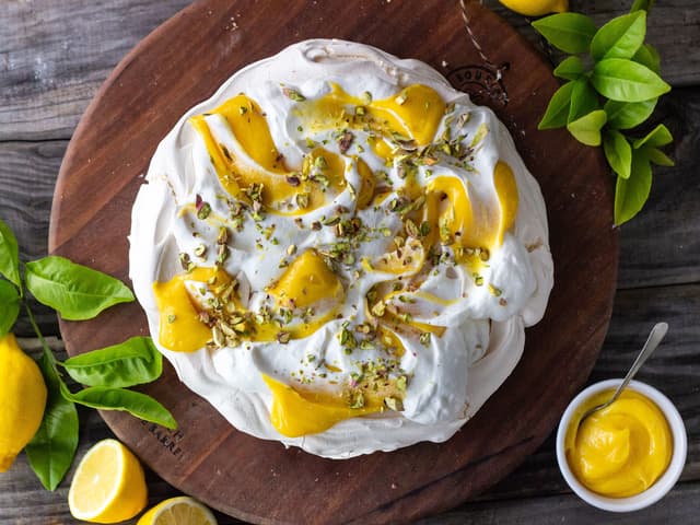 Bruk en skje og og legg pisket krem og lemon curd i topper rundt om på den avkjølte marengsen. Bruk så skjeen til å dra over, og lage et pent mønster av de hvite og gule.
