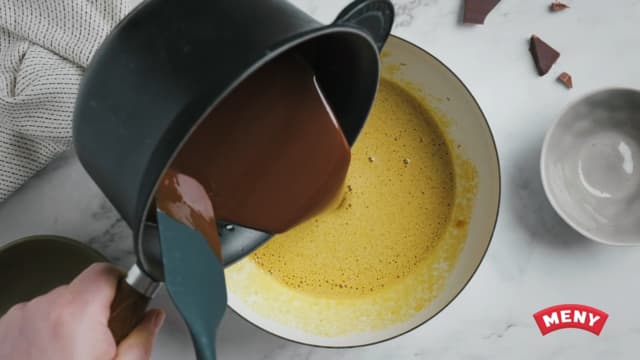 Ha den smeltete sjokoladen over i bollen med pisket egg og sukker, og bland godt.