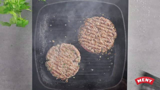 **Angusburgere:** Grill eller stek hamburgerne til de er gylne, gjennomstekte og saftige i midten. Ha på osteskivene og la dem smelte før servering.