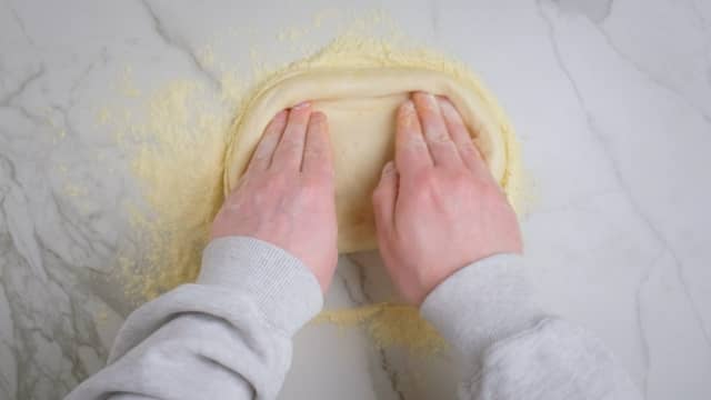**Forme deigen:** Form deigen med fingrene, ved å presse deigen utover. Du kan også løfte den opp og dra forsiktig i deigen. Ikke bruk kjevle, da forsvinner de små luftboblene i kanten som gjør at du får luftig skorpe.