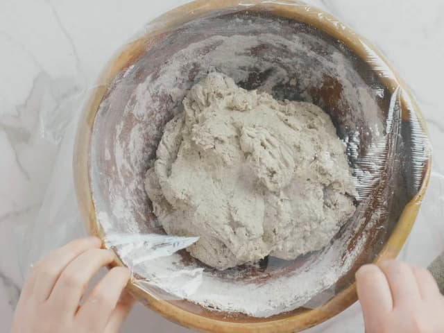 Dekk til bollen med et lokk eller plastfolie. La deigen stå på kjøkkenbenken i 12-18 timer.