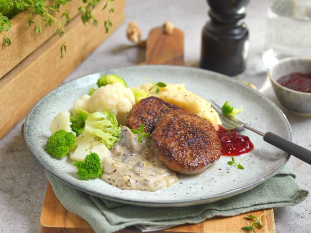 Server karbonader med sjampinjongstuing, potetmos og grønnsaker. Tyttebærsyltetøy er godt som tilbehør!