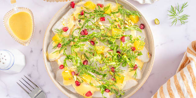 Fordel finhakket hjertesalat, granateplekjerner, noen appelsinbiter, nøtter og dill på hver tallerken.