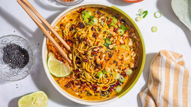 Anrett nudlene og sausen i to skåler, og topp med revet gulrot, chilicrisp, sprøstekt løk, vårløk og peanøtter.