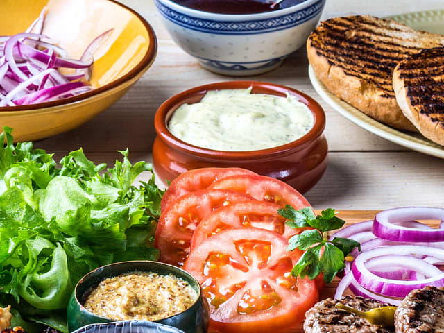**Tilbehør:** Gjør klart tilbehøret til burgerne, så du raskt kan montere dem når kjøttet er klart. Skjær tomat og rødløk i tynne skiver, og finn frem det du ønsker at dressing og annen topping.