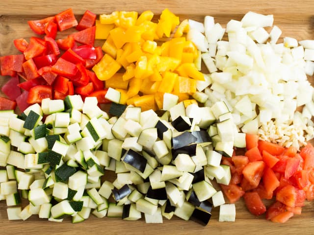 Flå tomatene, fjern kjernen og grovhakk tomatkjøttet. Rens og skjær grønnsakene i pene, jevne biter eller terninger.