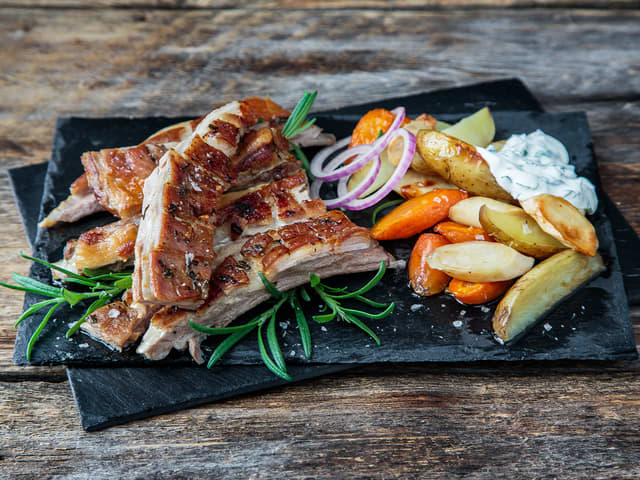 Del lammeribben i serveringsstykker ved å føre kniven nedover langs bena. Server med de møre rotgrønnsakene og urtedippen.