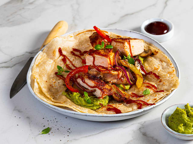 Legg guacamole, stekte kyllingstrimler og grønnsakene på varme hvetetortillas.