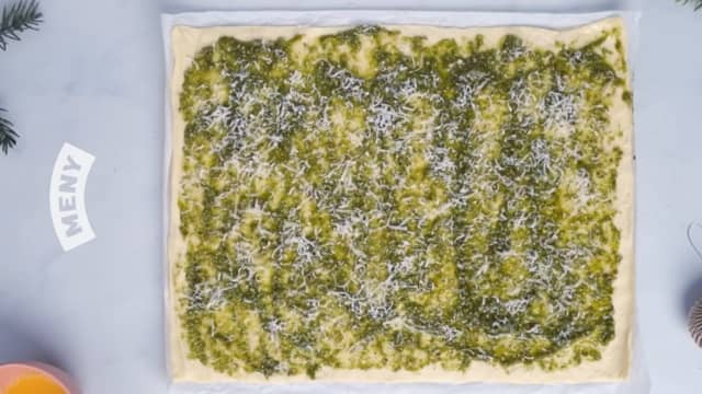 Rull ut den ene pizzadeigen, og dekk hele bunnen med pesto.