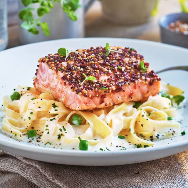 Fordel kremet pasta og erter på tallerkener og legg på den stekte laksen. Topp gjerne med fersk gressløk og litt revet parmesan.