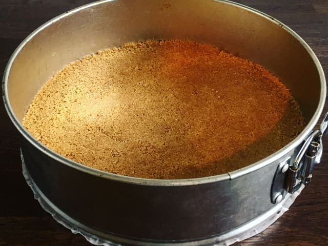 **Kjeksbunn:** Smelt smøret og bland med knust kjeks. Fordel kjeksbunnen i en rund kakeform med 24 cm i diameter. Trykk kjeksblandingen godt ned med fingrene.