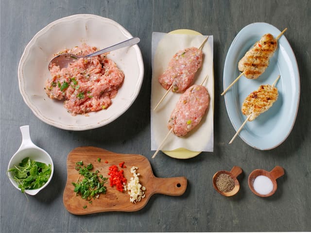 Finhakk 2 fedd hvitløk, oregano og chili, grovhakk nøttene og bland med kyllingkjøttdeig. Klem lange boller rundt grillpinner, og stek dem i en grillpanne, ca. 3 min. på hver side. Krydre med salt og pepper.