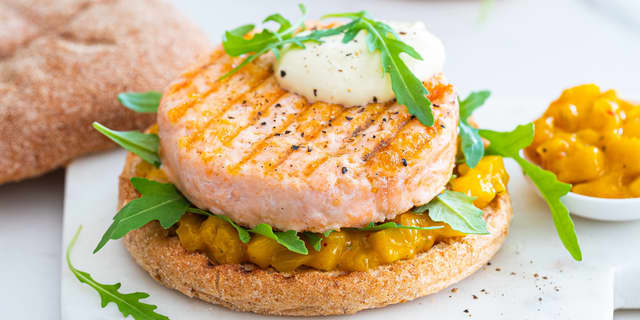Anrett bunnen av burgerbrødene og topp med mangosalsa, aioli og lakseburger.