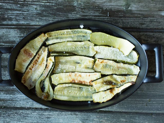 Bruk en ildfast form som rommer ca. 1–1,5 l. Drypp litt olje i bunnen av formen og legg squashskivene utover bunnen.