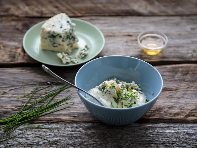 Bland rømme, yoghurt, roquefort, eplecidereddik, gressløk og epleterninger i en skål. Smak til med salt og pepper.