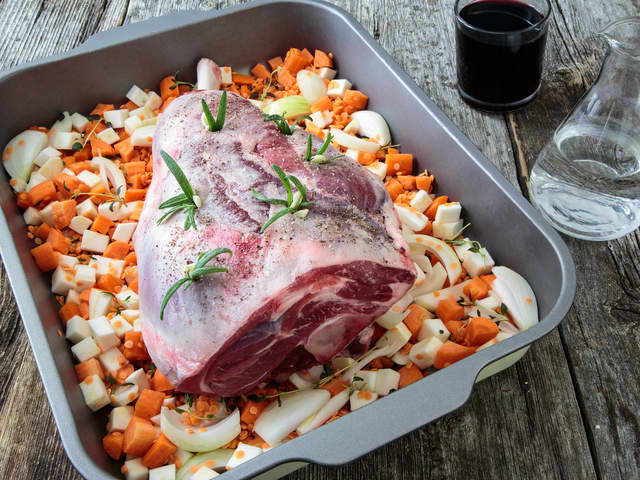Ha grønnsakene i en ildfast form med laurbærblader, og hell over vannet. Legg lammelåret på toppen og sett inn et  steketermometer i den tykkeste delen av låret (pass på at du ikke treffer benet).