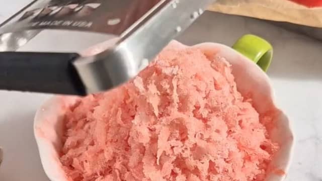 Ta vannmelonbitene ut av fryseren og rasp dem over et glass eller en skål med et rivjern.