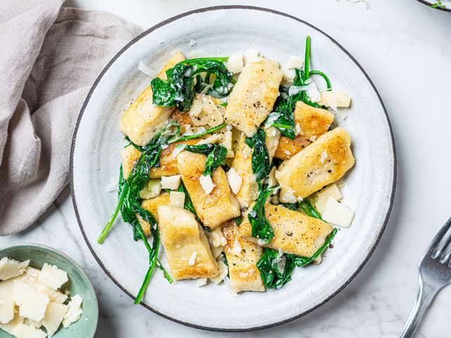 Når smøret begynner å bli brunt og lukte nøtteaktig, tilsetter du spinaten og blomkålgnocchien. Server med revet parmesan.
